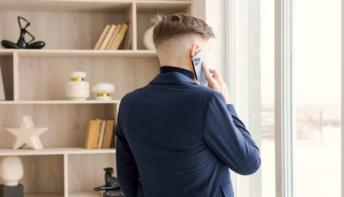 Mężczyzna prowadzący rozmowę telefoniczną przy oknie – pierwszy krok w procesie konsultacji prawnej